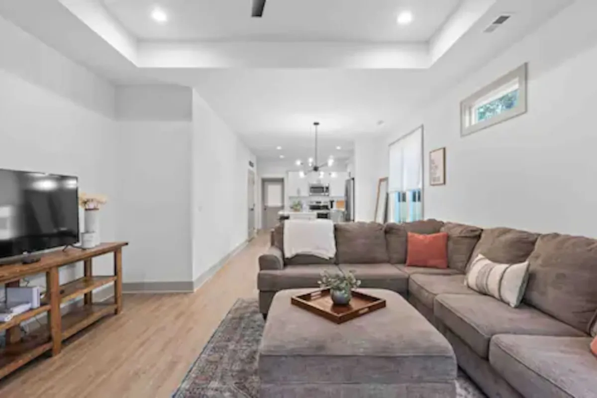 A comfortable living room featuring a plush sofa, stylish coffee table, and a television, all arranged in an inviting, open space designed for relaxation or quiet evenings in. The natural lighting and clean decor create an atmosphere of calm and comfort.