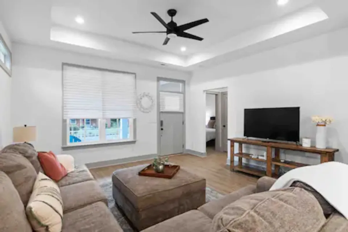 A cozy family room with a plush sofa, coffee table, flat-screen TV, and a window offering a view outside. The ambiance is casual and inviting, creating an ideal spot for winding down after busy days exploring the area.