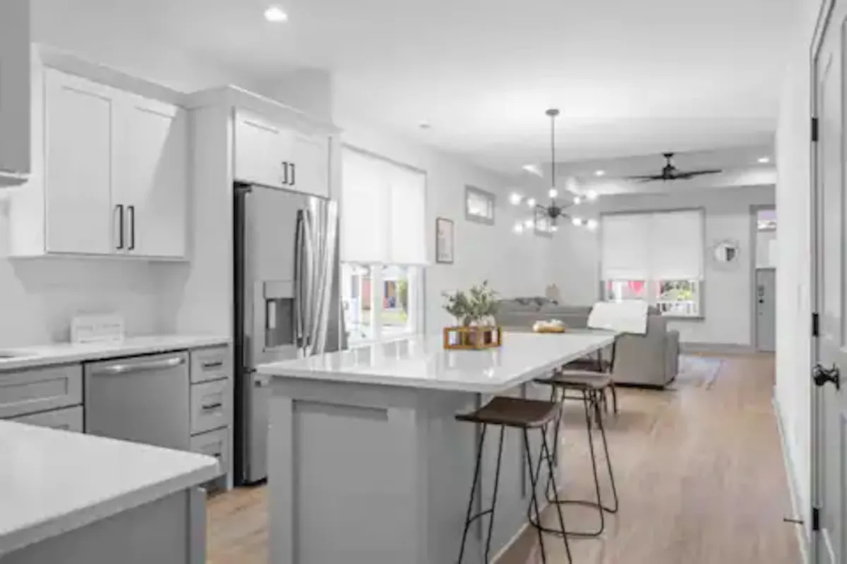 The hero image features a bright, open-concept kitchen with a spacious island, modern appliances, and comfortable seating, all illuminated by stylish light fixtures. The layout invites guests to gather, cook, and enjoy meals together, creating a warm and inviting atmosphere ideal for groups or families.