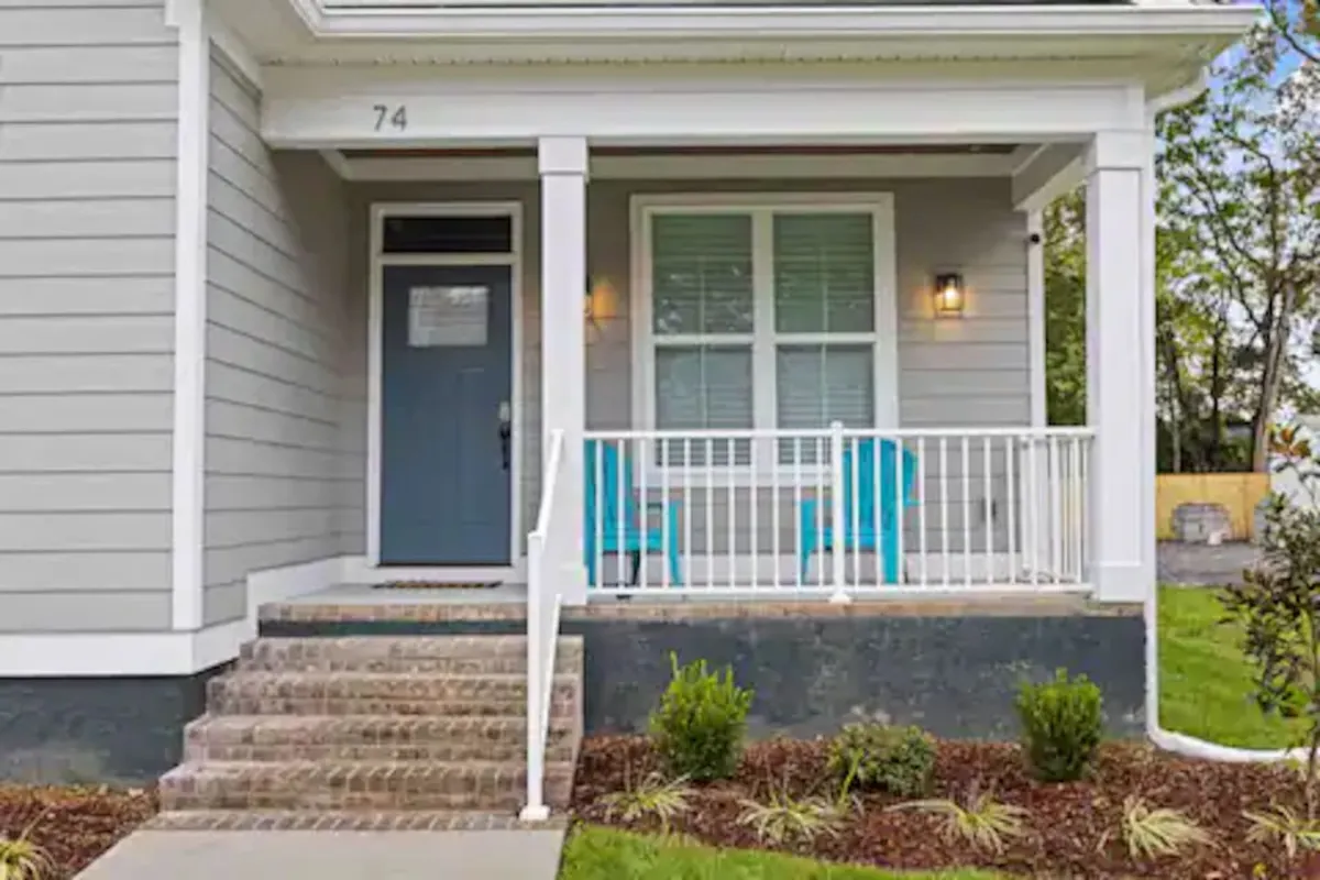 An inviting front porch with blue chairs positioned near the front door, bathed in natural light. The scene suggests both privacy and an inviting entry, with an atmosphere that feels friendly yet secure.